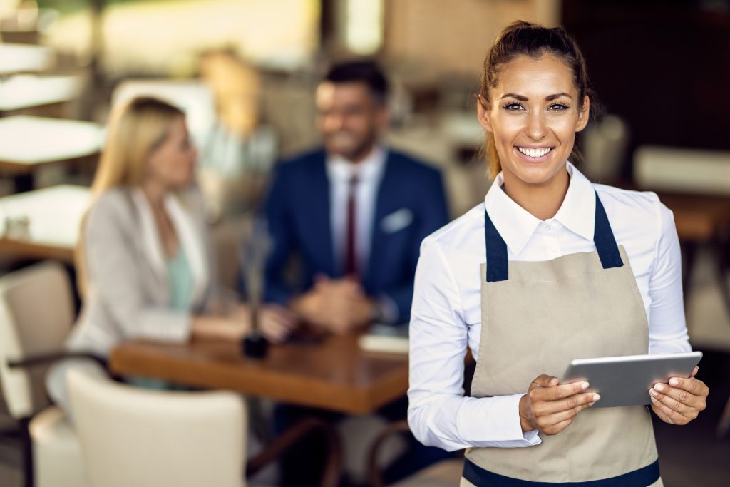 young happy waitress using touchpad while working cafe