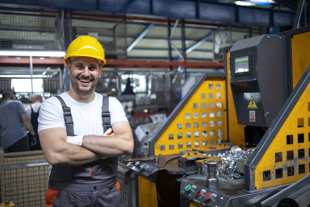 portrait factory worker with arms crossed standing by industrial machine production plant 1